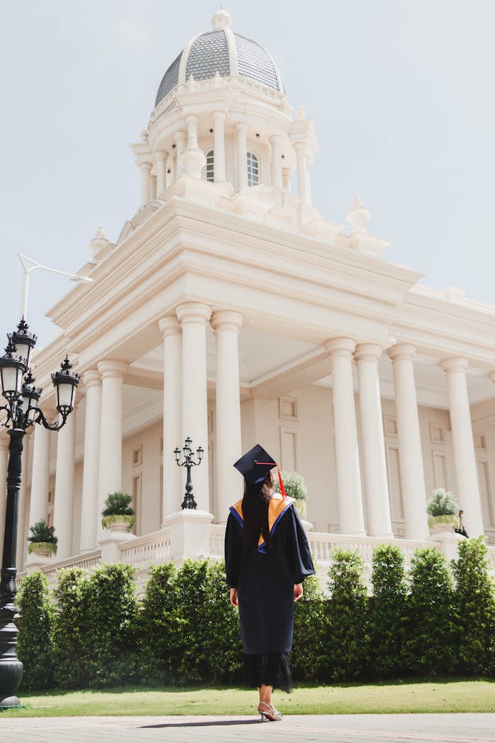 Graduating student in gown and cap in front of a university building in Phnom Penh.